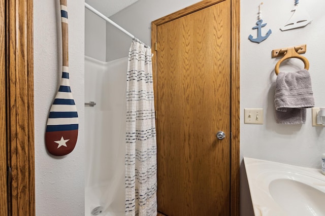 bathroom with a shower with shower curtain and a textured ceiling