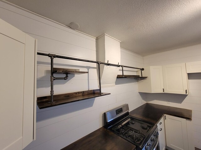 kitchen with a textured ceiling, white cabinetry, and black range with gas cooktop