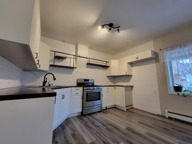 kitchen with dark hardwood / wood-style flooring, a baseboard heating unit, sink, stainless steel range oven, and white cabinetry