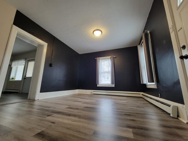 spare room with baseboard heating, vaulted ceiling, and hardwood / wood-style flooring