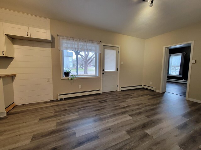 unfurnished dining area featuring dark hardwood / wood-style floors and a baseboard heating unit