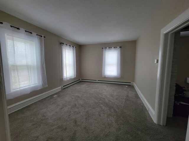 carpeted spare room with a healthy amount of sunlight, a textured ceiling, and a baseboard radiator