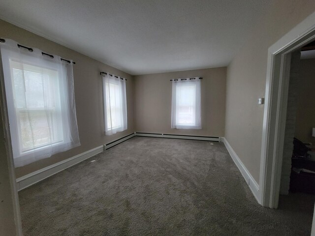 carpeted spare room with a textured ceiling, plenty of natural light, and a baseboard heating unit