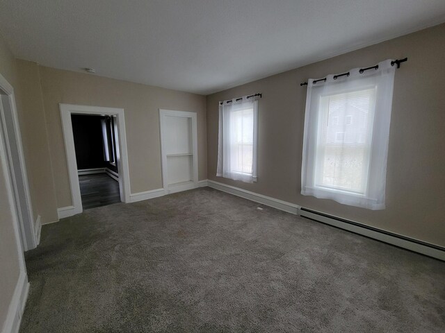 carpeted empty room with a baseboard radiator