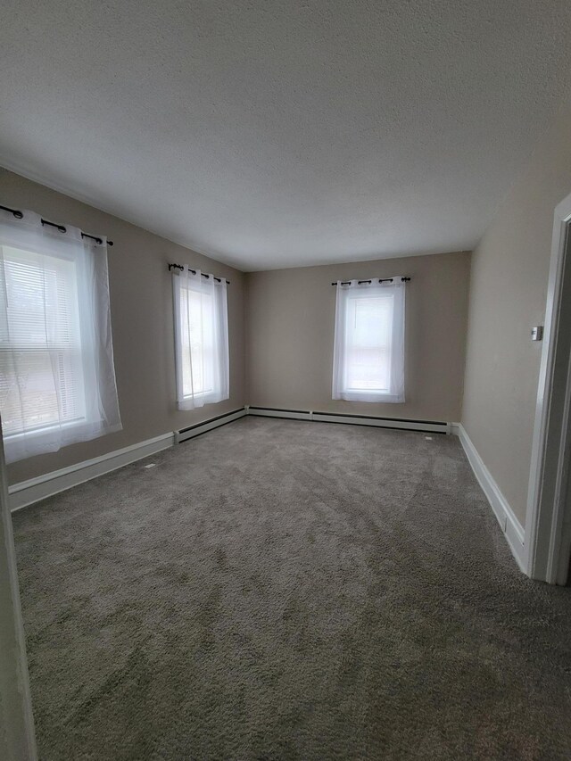 unfurnished room featuring plenty of natural light, dark carpet, and a textured ceiling