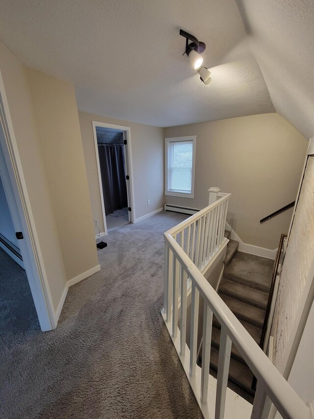 staircase featuring carpet, a textured ceiling, vaulted ceiling, and a baseboard heating unit