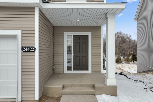 snow covered property entrance with a garage