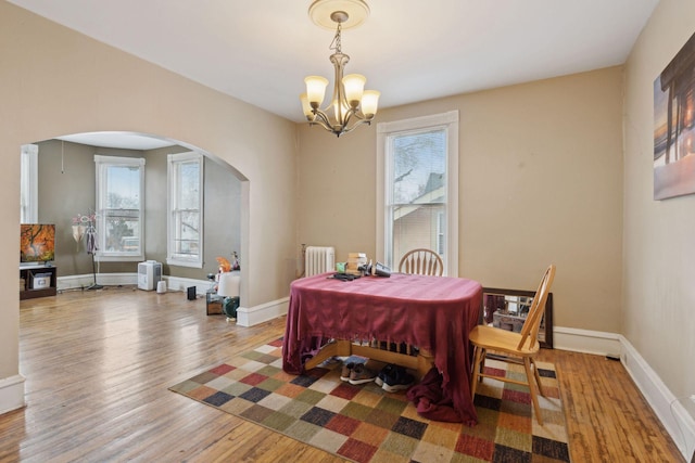 dining space featuring hardwood / wood-style flooring, radiator, and a notable chandelier