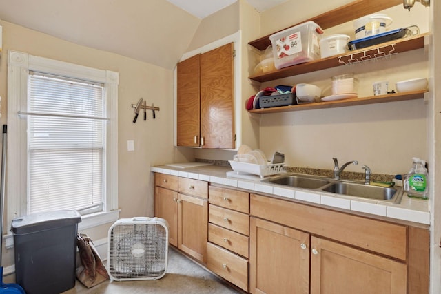 kitchen featuring vaulted ceiling, tile countertops, and sink