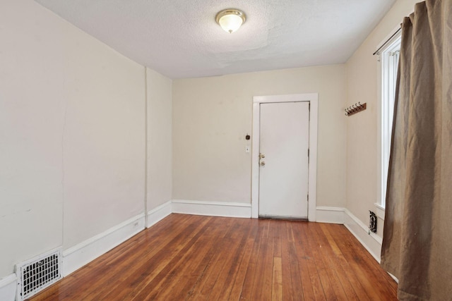 empty room with dark hardwood / wood-style flooring and a textured ceiling