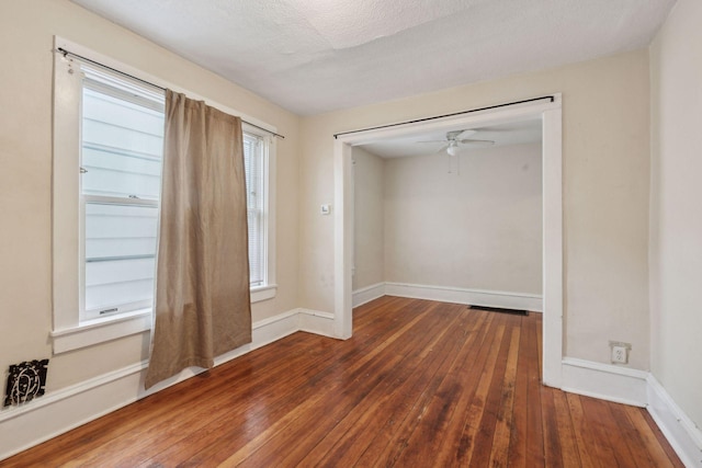 unfurnished room with dark hardwood / wood-style floors, a textured ceiling, and ceiling fan