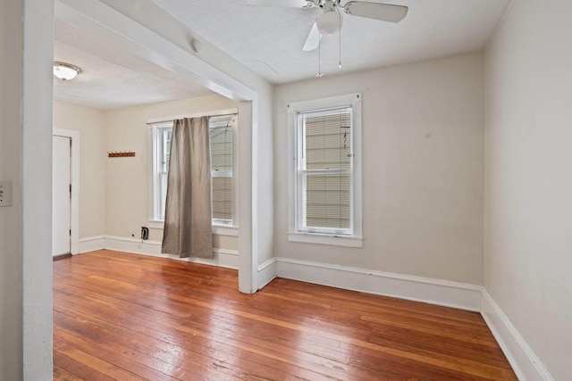 empty room with ceiling fan, wood-type flooring, and a textured ceiling