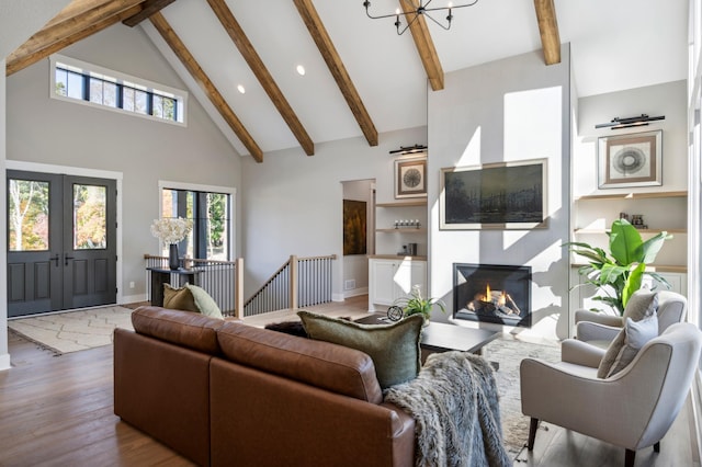 living room featuring beamed ceiling, a chandelier, high vaulted ceiling, and light hardwood / wood-style floors