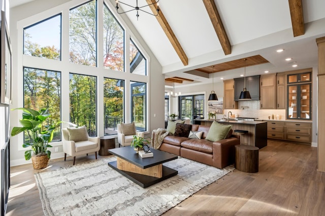 sunroom featuring lofted ceiling with beams, sink, and a chandelier