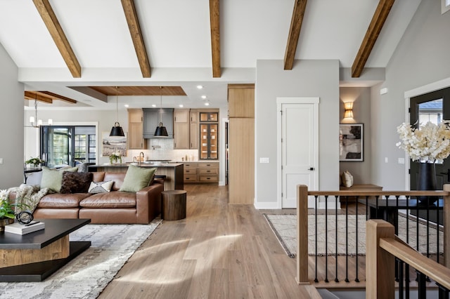 living room with an inviting chandelier, beam ceiling, and light hardwood / wood-style flooring