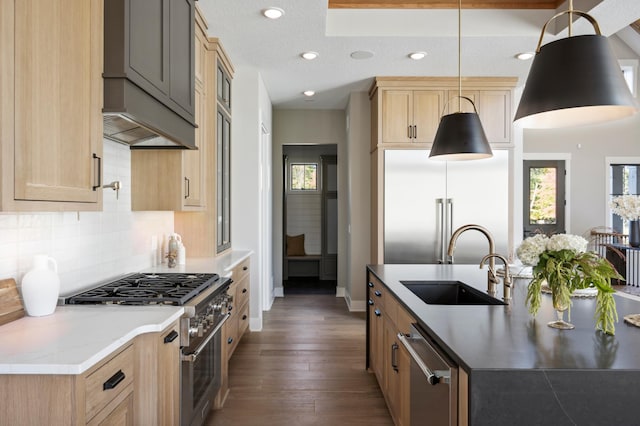 kitchen featuring decorative light fixtures, sink, dark stone countertops, backsplash, and premium appliances