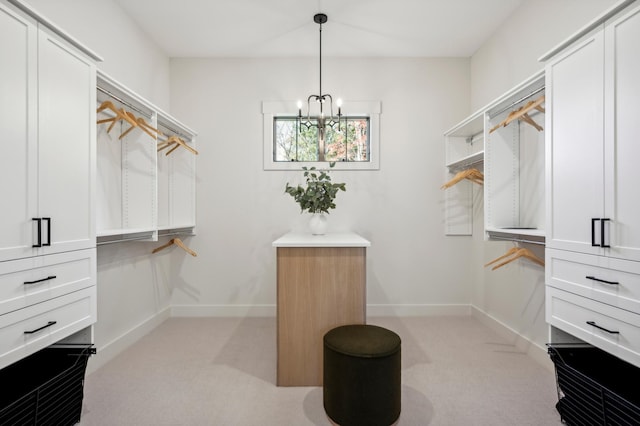 walk in closet with an inviting chandelier and light colored carpet