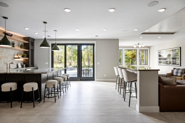 kitchen with stone countertops, decorative light fixtures, a breakfast bar, and a wealth of natural light