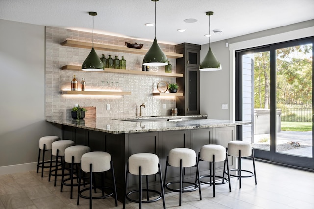 bar with light stone countertops, pendant lighting, and backsplash