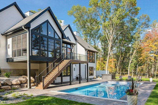 back of house with a swimming pool with hot tub, a patio area, and a sunroom