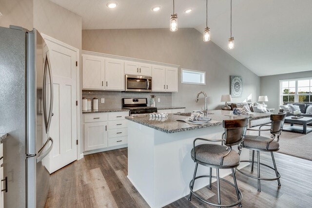 kitchen featuring hanging light fixtures, white cabinets, sink, and stainless steel appliances