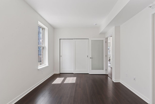 2825 Colfax Ave S Unit 211, Minneapolis, MN 55408 - unfurnished bedroom featuring multiple windows, dark wood-type flooring, baseboards, and a closet
