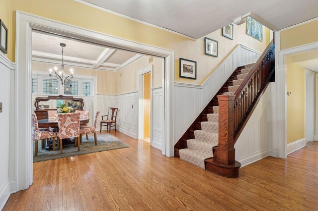 1941 James Ave S, Minneapolis, MN 55403 - dining space with stairs, wood finished floors, a chandelier, a decorative wall, and ornamental molding
