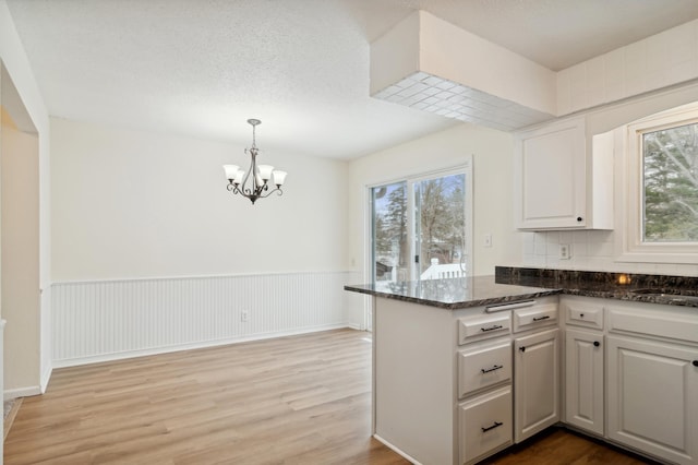 kitchen with kitchen peninsula, light hardwood / wood-style floors, white cabinetry, and plenty of natural light