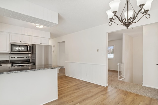 kitchen with appliances with stainless steel finishes, light hardwood / wood-style flooring, white cabinetry, and pendant lighting