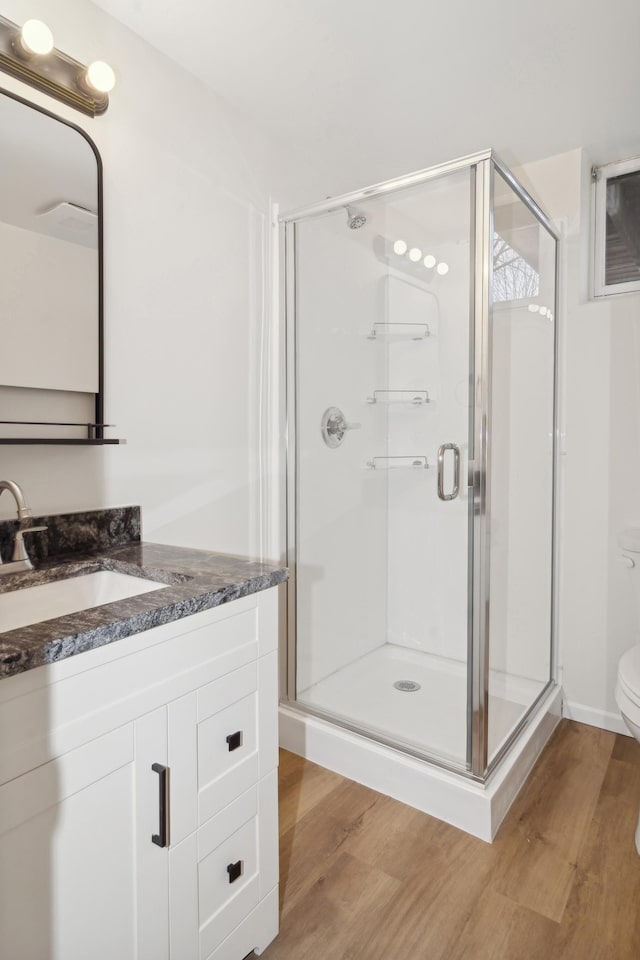 bathroom featuring vanity, wood-type flooring, an enclosed shower, and toilet