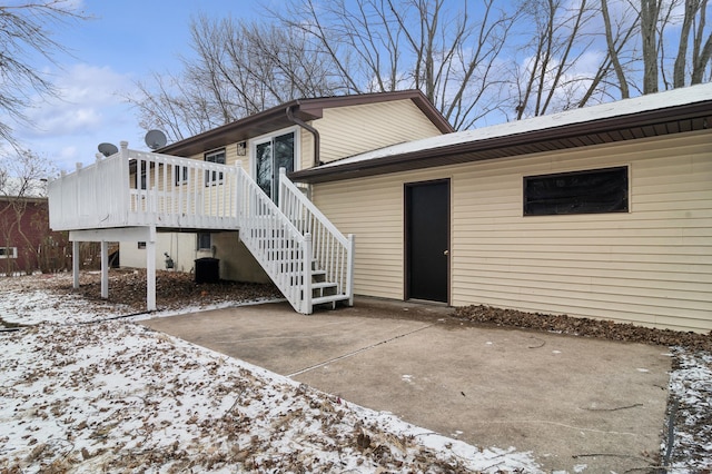 snow covered rear of property featuring a patio area and a deck