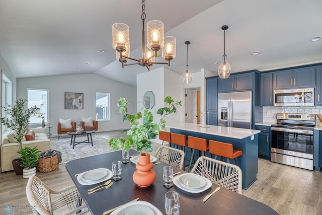 dining room with a chandelier, vaulted ceiling, and light hardwood / wood-style flooring