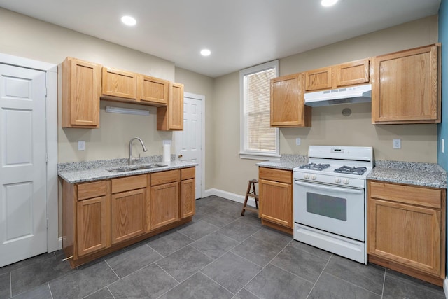 kitchen featuring white gas stove, dark tile patterned floors, light stone countertops, and sink