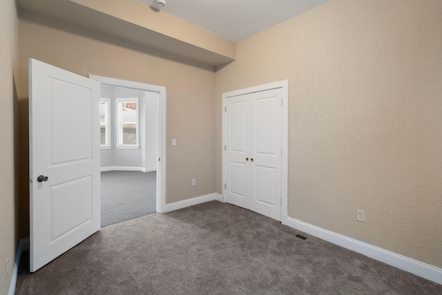 unfurnished bedroom featuring dark colored carpet and a closet