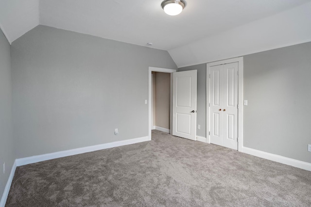 unfurnished bedroom with carpet flooring, a closet, and lofted ceiling