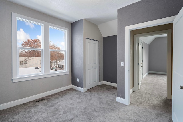 unfurnished bedroom featuring a closet, light colored carpet, and lofted ceiling