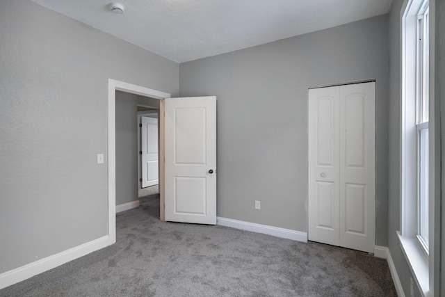 unfurnished bedroom with light colored carpet and a closet