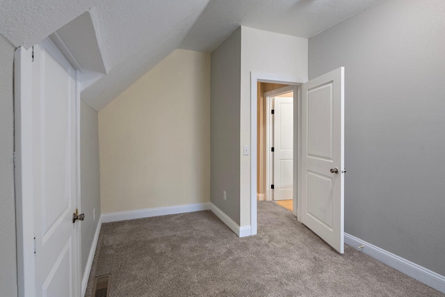 additional living space with a textured ceiling, light carpet, and lofted ceiling