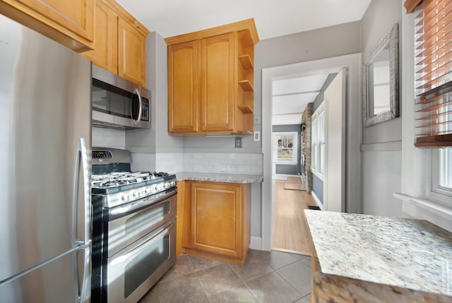 kitchen with light stone counters, light tile patterned floors, and stainless steel appliances