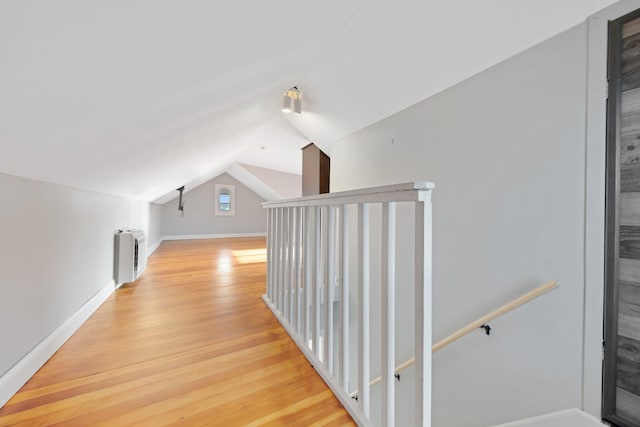 hallway with radiator, light hardwood / wood-style flooring, and vaulted ceiling