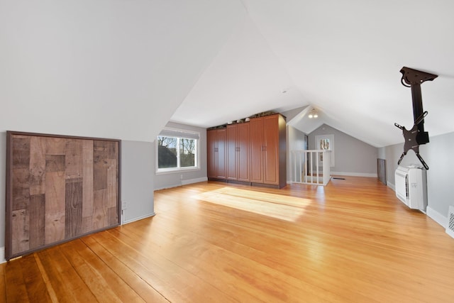 bonus room with light wood-type flooring and vaulted ceiling