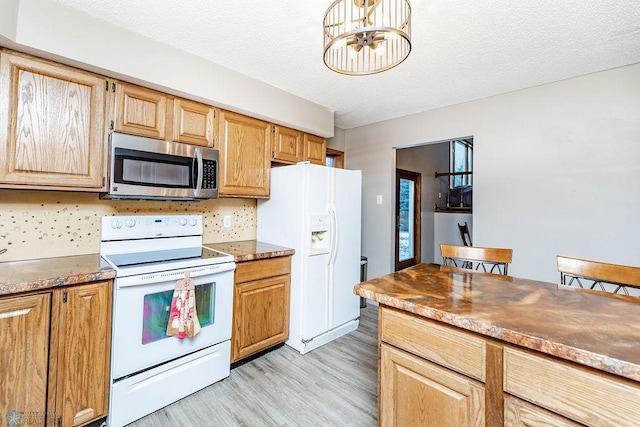 kitchen featuring a chandelier, light wood-type flooring, white appliances, and a textured ceiling