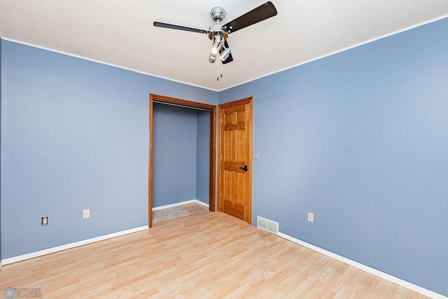 empty room with visible vents, a ceiling fan, a textured ceiling, wood finished floors, and baseboards