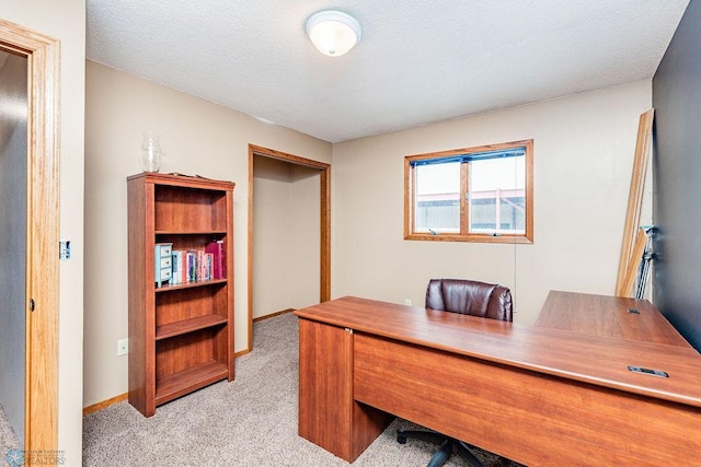 home office featuring light carpet, a textured ceiling, and baseboards