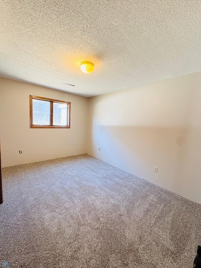 carpeted empty room with a textured ceiling