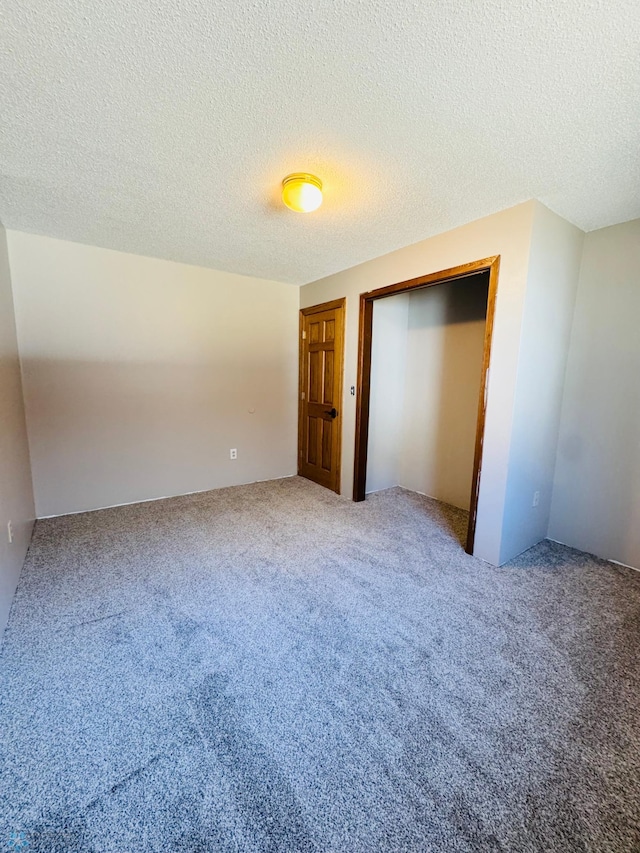 unfurnished bedroom featuring a textured ceiling, a closet, and carpet flooring