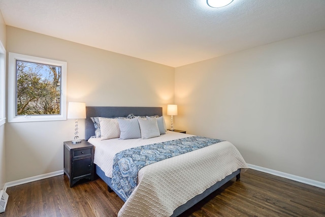 bedroom with dark hardwood / wood-style flooring and a baseboard heating unit