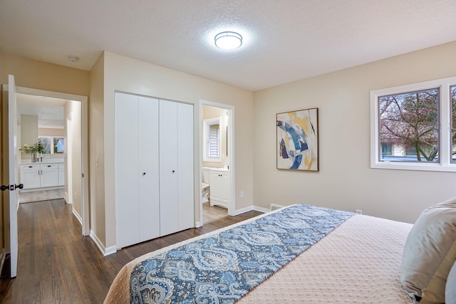 bedroom featuring dark hardwood / wood-style flooring, a textured ceiling, connected bathroom, and a closet