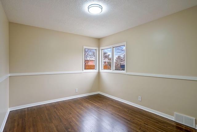 empty room with a textured ceiling and dark wood-type flooring