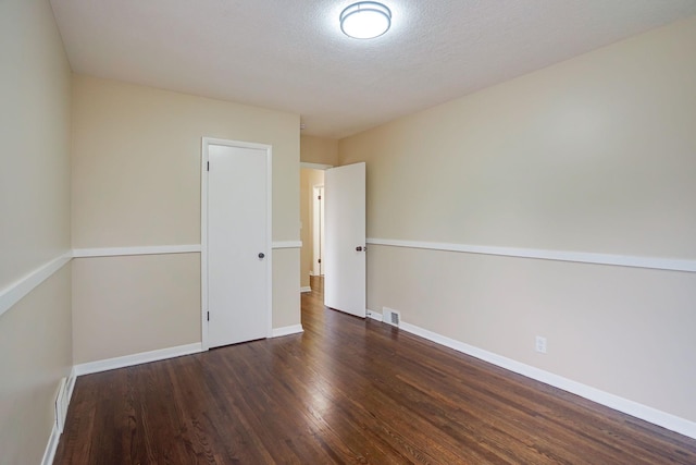 unfurnished room with dark hardwood / wood-style flooring and a textured ceiling